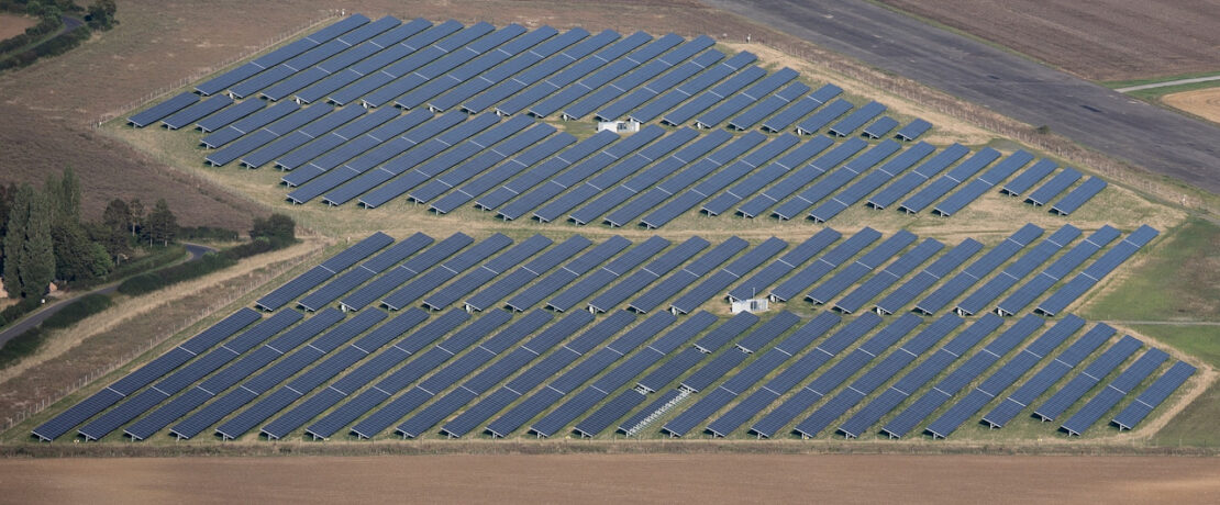 An aerial view of a large solar farm located in a rural setting.