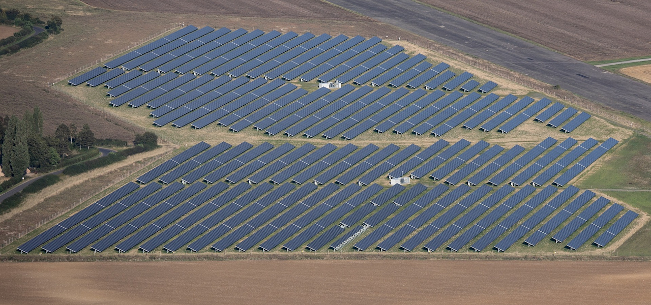 An aerial view of a large solar farm located in a rural setting.